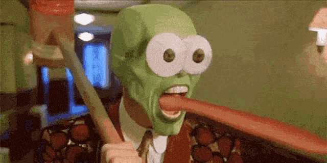 a man wearing a mask is sticking out his tongue while holding a stick .