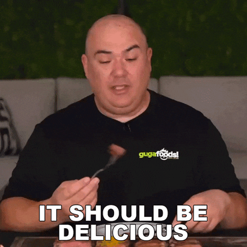 a man wearing a black shirt that says ' it should be delicious ' on it