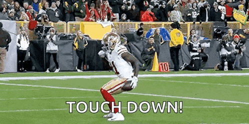 a football player is kneeling on the field with the words `` touch down '' written on it .
