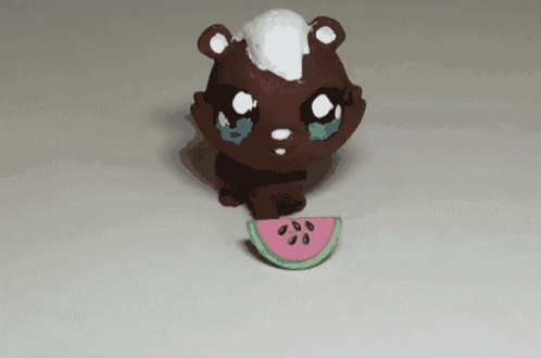 a toy bear with a watermelon slice in its mouth