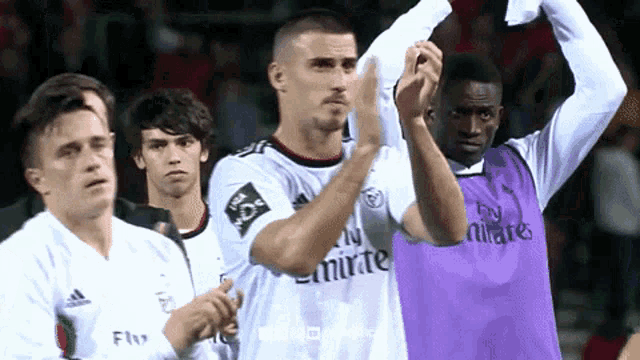 soccer players wearing fly emirates jerseys are clapping