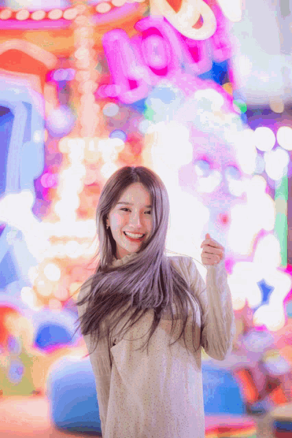 a woman is smiling in front of a sign that says ' love '