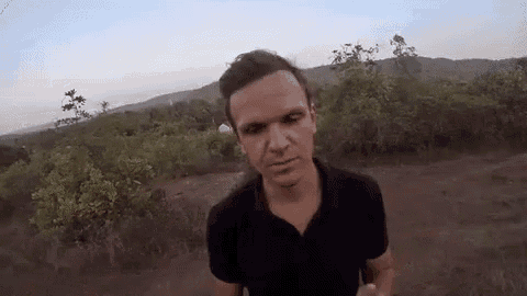 a man in a black shirt is standing in the middle of a field .
