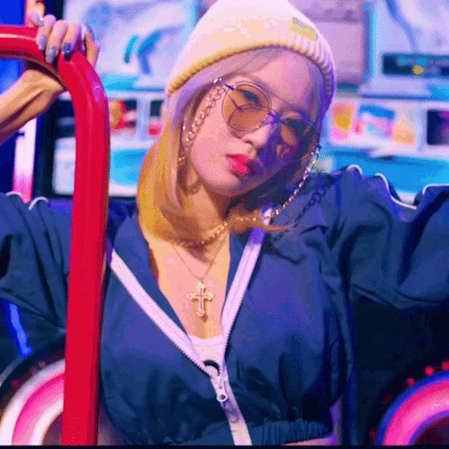 a woman wearing a beanie and sunglasses has a cross necklace