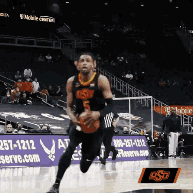 a basketball player with the number 5 on his jersey is dribbling the ball