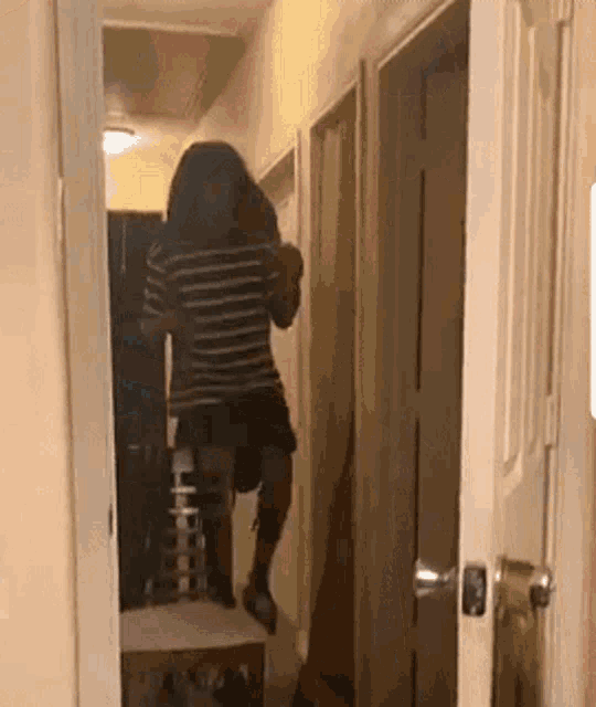 a woman in a striped shirt is standing in a hallway .