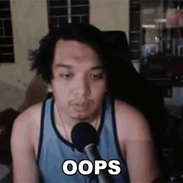 a man is sitting in front of a microphone with the word oops written on his face .