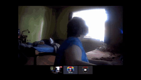 a man in a blue tank top is dancing in front of a window