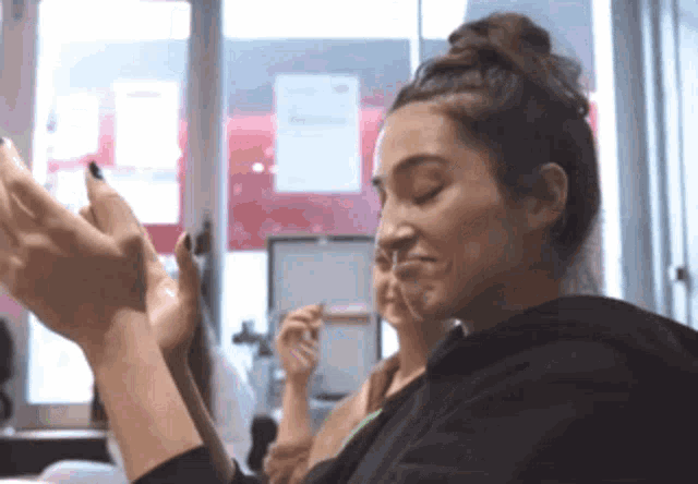 a woman in a black hoodie is clapping her hands together