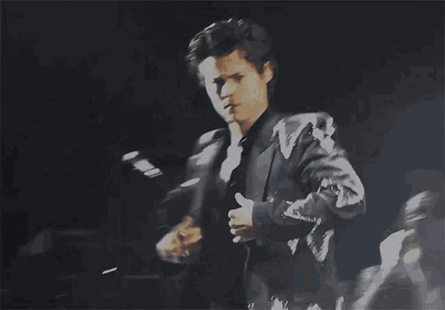 a man in a black suit is giving a thumbs up .