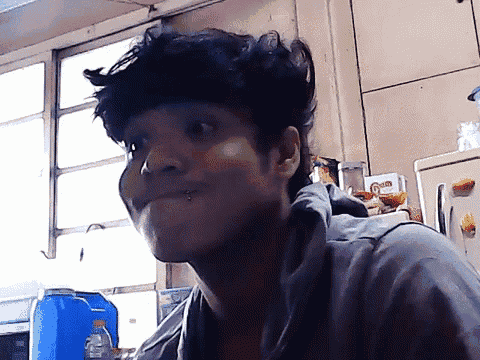a man with a piercing in his nose looks at the camera in a kitchen