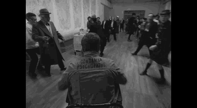 a man in a wheelchair has a jacket that says " condamna psychopathe " on the back