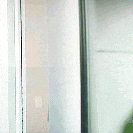 a man in a black shirt is peeking out from behind a door
