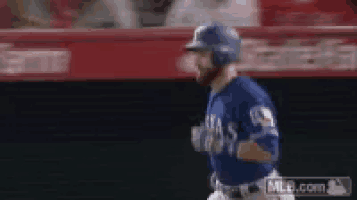 a baseball player wearing a blue jersey and a blue helmet is running on the field .