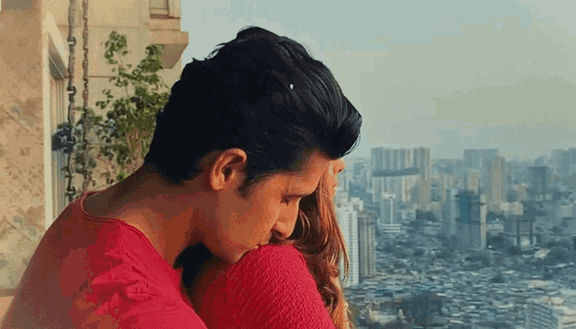 a man in a red shirt is hugging a woman