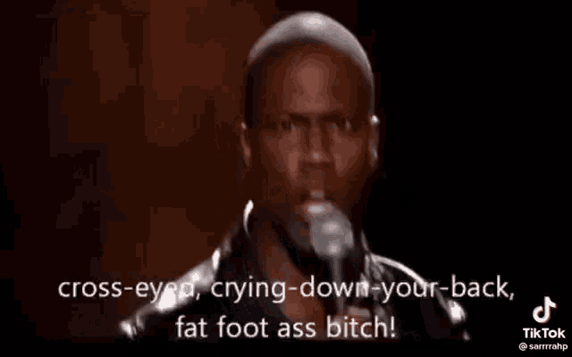 a man in a leather jacket is standing in front of a microphone and talking into it .