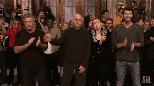 a group of people are standing in front of a crowd clapping .