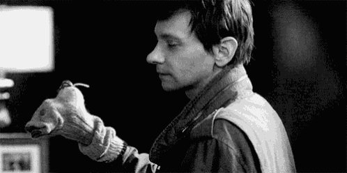 a black and white photo of a man holding a stuffed animal in his hand .