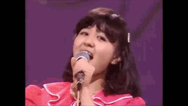 a woman is singing into a microphone on a stage .