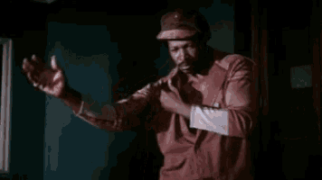 a man in a baseball cap is standing in a dark room