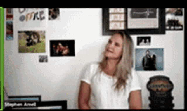 a woman in a white shirt is standing in front of a wall with pictures on it and the word office on it