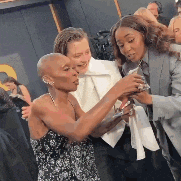 a woman with a shaved head is taking a selfie with two other women