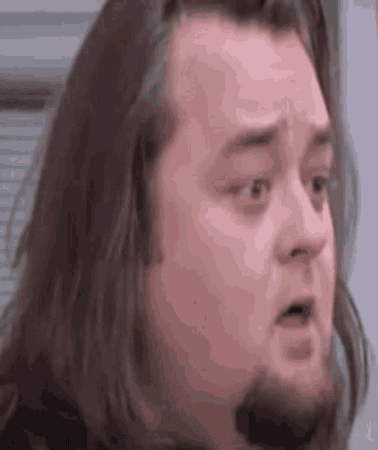 a man with a beard and long hair is making a funny face .