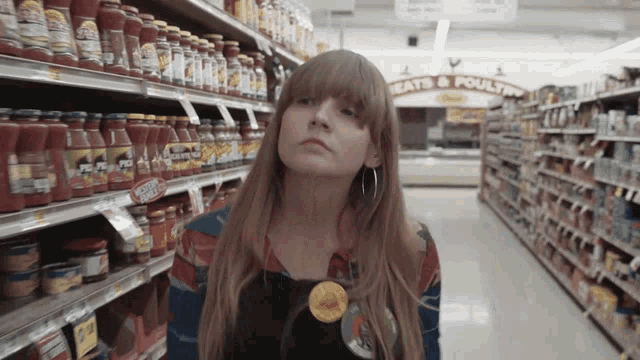 a woman stands in a grocery store aisle with a sign that says meats and poultry