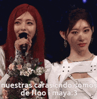 a woman with red hair is holding a microphone while another woman holds a bouquet of flowers