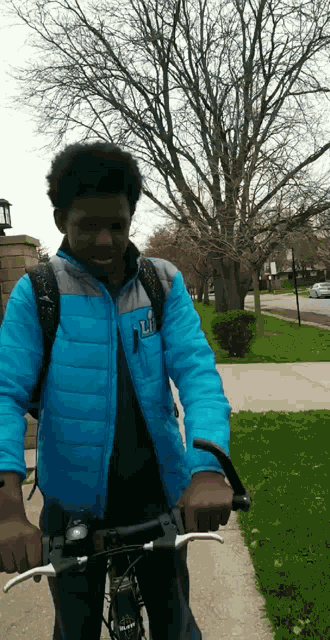 a young man wearing a blue jacket with the letter l on it is riding a bike