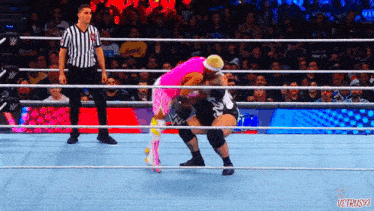 a wrestler in a pink outfit is being pinned by another wrestler in a black outfit