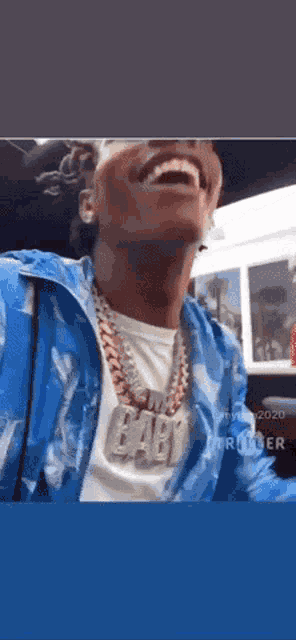 a man wearing a blue jacket and a necklace with the word baby on it .