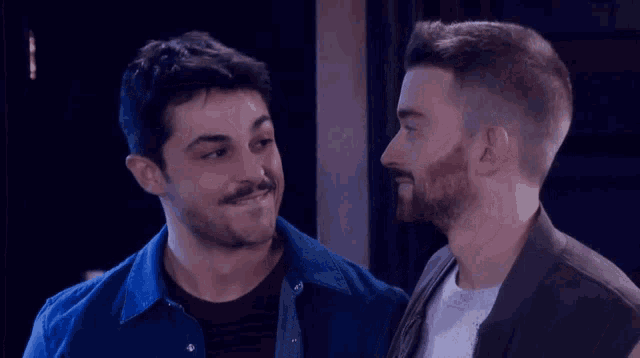two men are standing next to each other and smiling at the camera