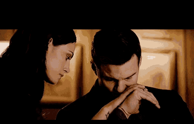 a man and a woman are looking at each other and the woman is holding the man 's hand