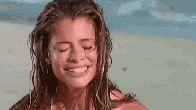 a woman is crying on the beach with her eyes closed and smiling .