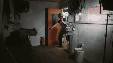 a man wearing a helmet is standing in a dark room with a machine .