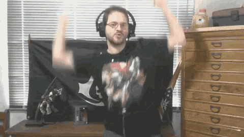 a man wearing headphones and a black shirt with a bat on it is dancing