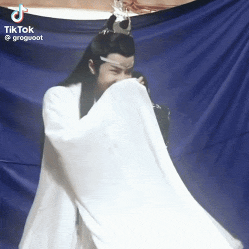 a man in a white robe is covering his face with a white cloth ..