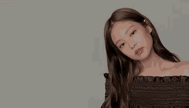 a woman with long hair is wearing a black off the shoulder top .