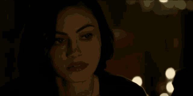 a close up of a woman 's face in a dark room with a blurry background .