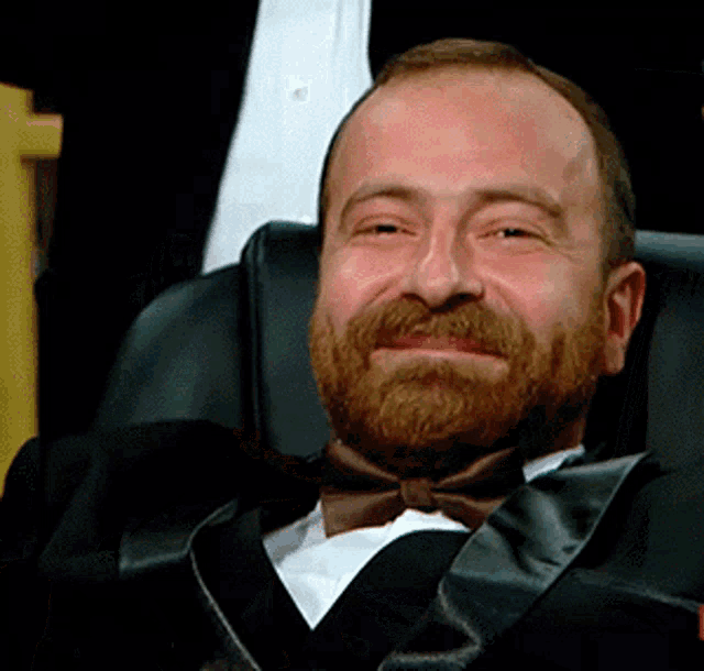 a man in a tuxedo and bow tie smiles for the camera