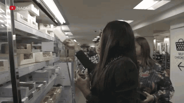 two women are shopping in a store with a sign that says self check in the corner