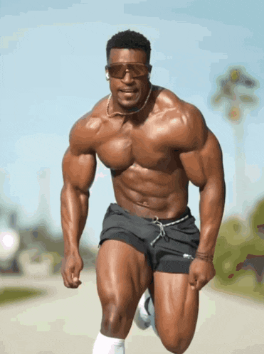 a muscular man wearing sunglasses and shorts is running down a street