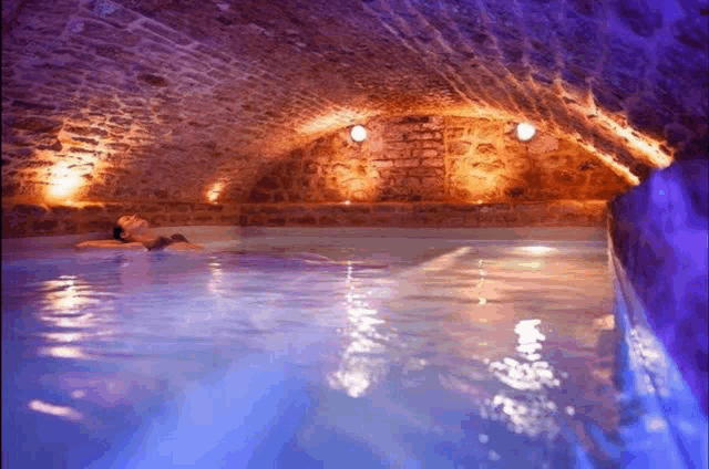 a woman is laying in a swimming pool surrounded by bricks