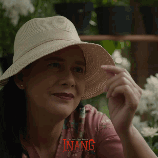 a woman wearing a hat and a pink shirt with the word inang on it