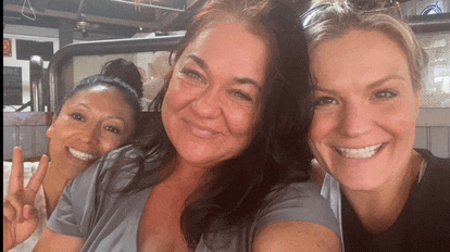 three women are posing for a picture and one of them is giving a peace sign