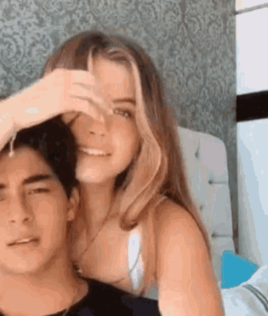a man and a woman are sitting next to each other in a bedroom .
