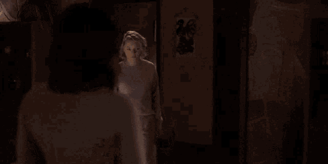 two women are talking to each other in a dark room .