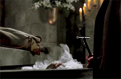 a man is holding a cross in front of a corpse