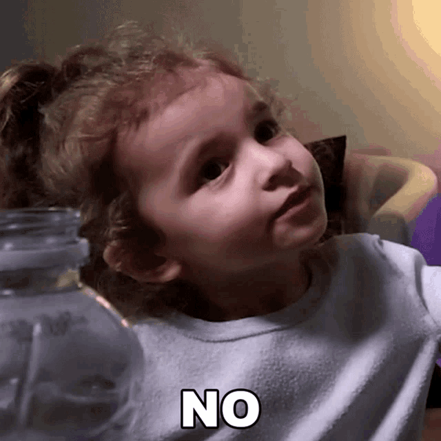 a little girl says no in front of a glass bottle
